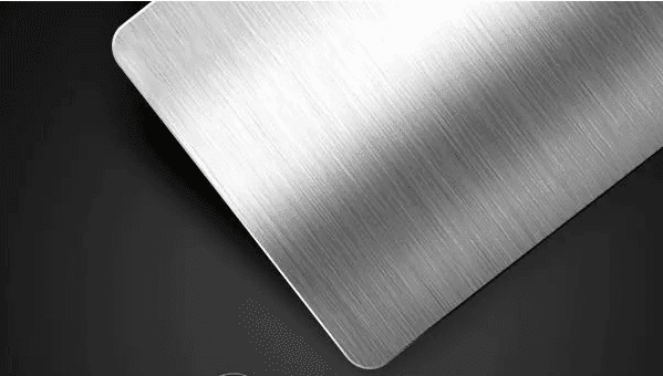 Close-up of a polished metal surface with a brushed texture on a dark background.